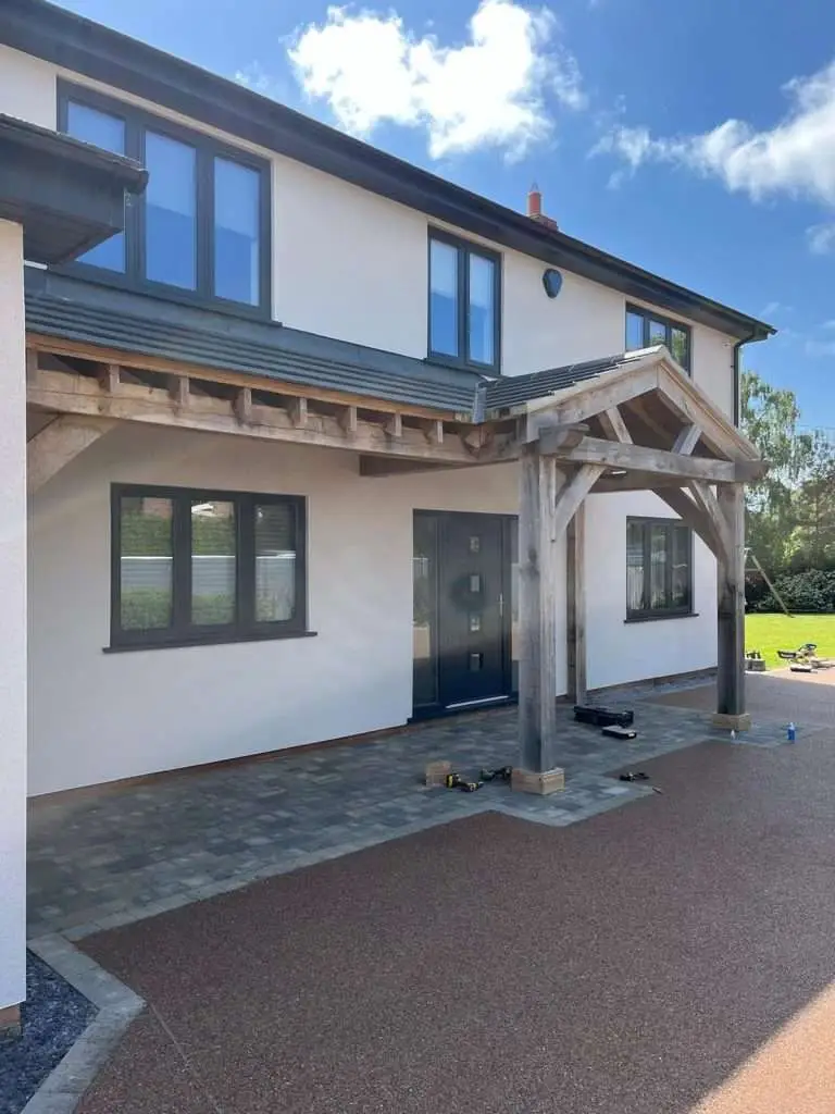 Timber-framed entrance canopy and windows on a rendered house
