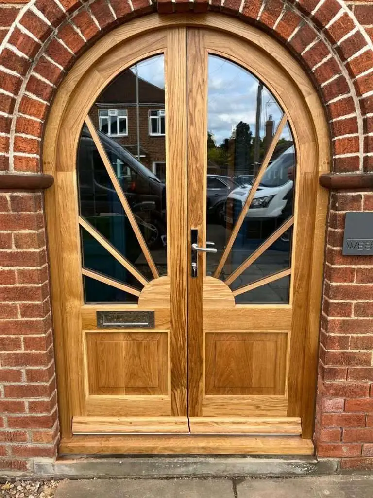 Arched timber double doors with decorative glazed panels