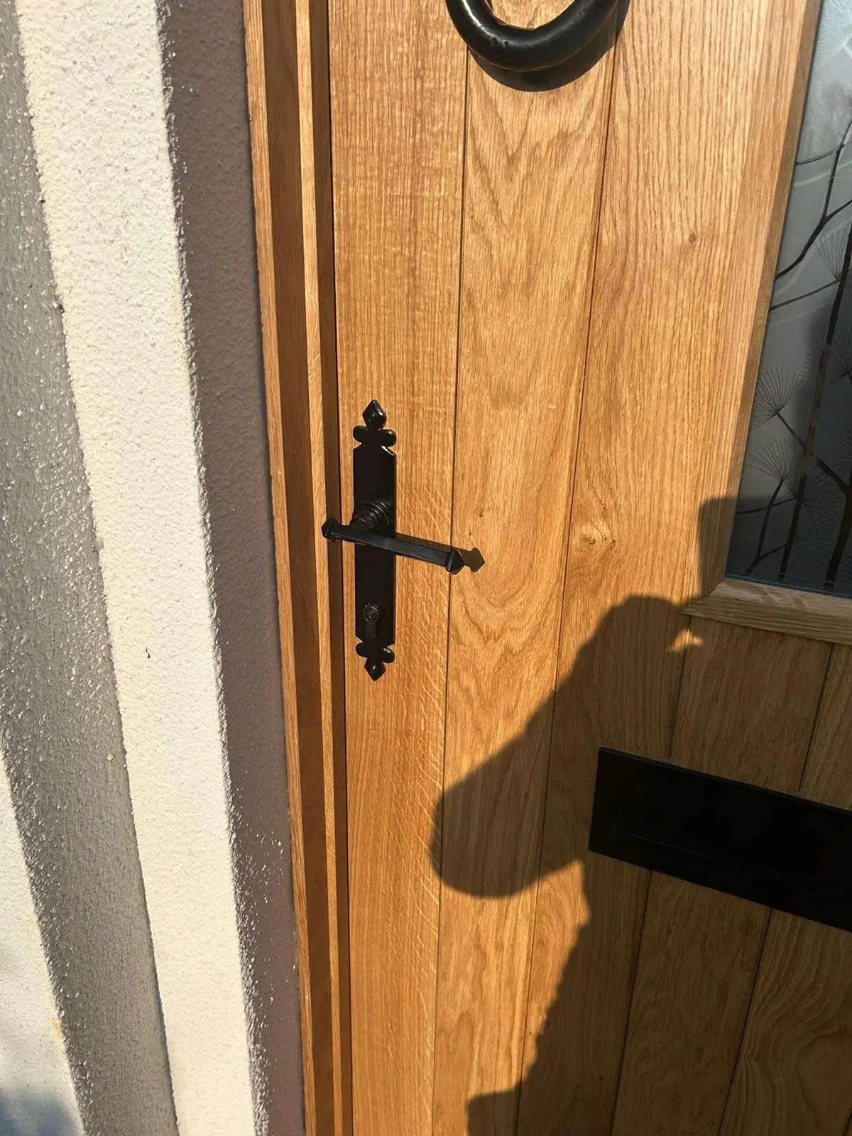 Close-up of an oak entrance door with black ironmongery