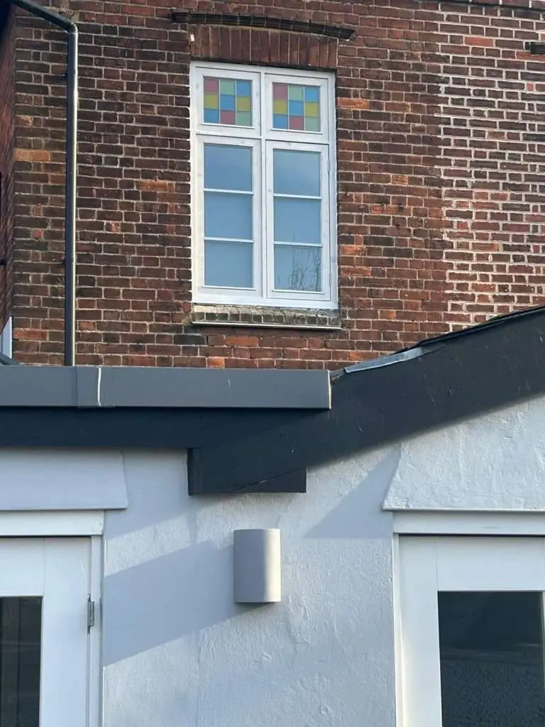 White timber window with coloured upper glazing set into a brick wall