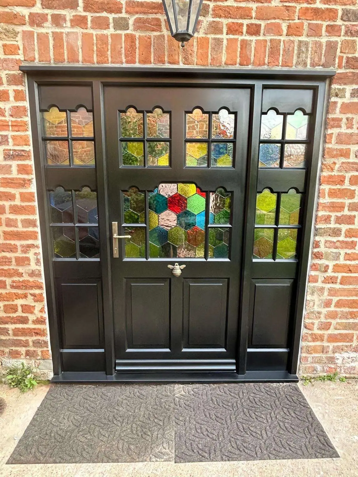 Black painted entrance door and side screens with decorative coloured glazing