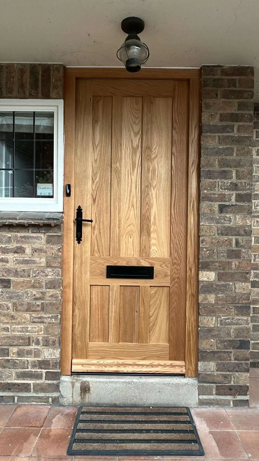 Oak four-panel timber entrance door with letterplate in a brick opening