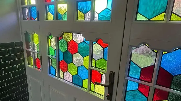 Close-up of hexagonal stained glass and a handle on a white painted timber door