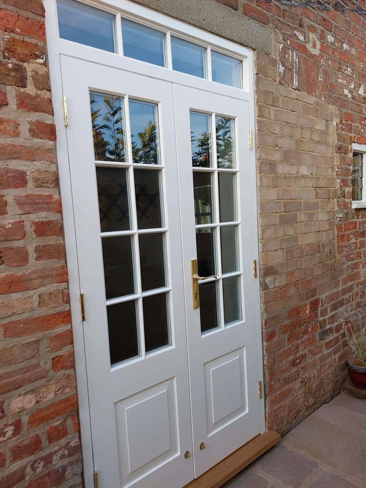White glazed timber entrance door and fanlight in a brick opening