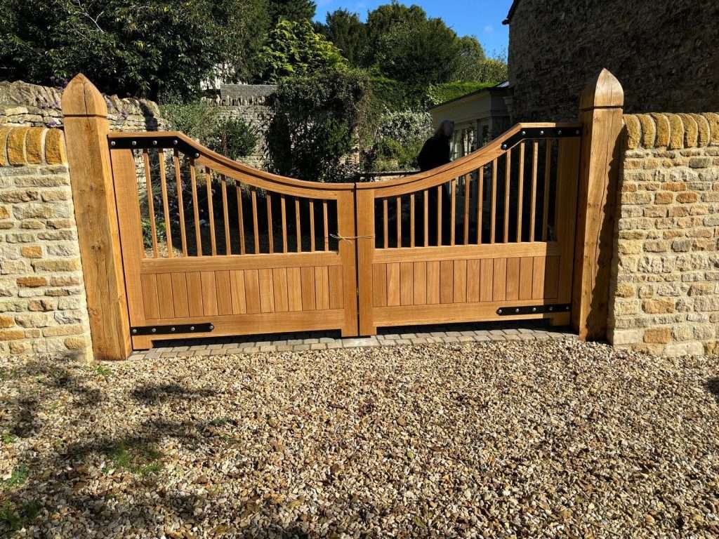 Pair of shaped timber driveway gates between stone walls