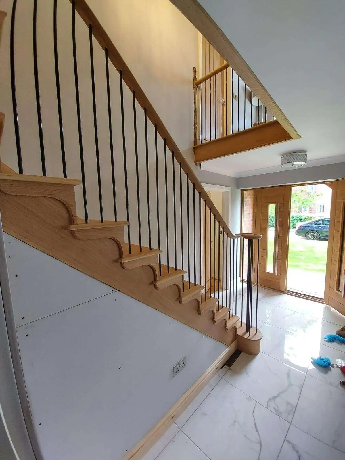 Oak staircase and balustrade beside a bright entrance hall
