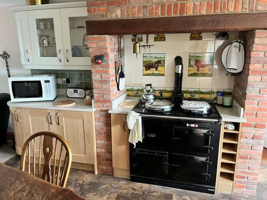 Traditional fitted kitchen with timber worktops beside a brick fireplace