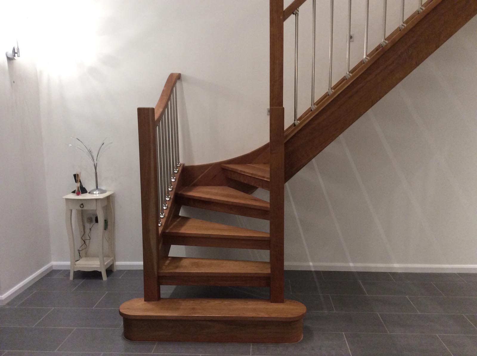 Curved cherry timber staircase with open risers and slender balusters